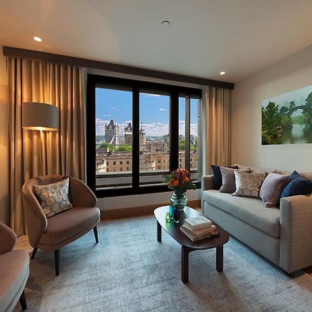ทาวเวอร์ สวีท บาย บลู ออร์คิด Hotel ลอนดอน ภายนอก รูปภาพ The photo depicts a modern living room with a contemporary design. It features two stylish, circular chairs and a comfortable sofa adorned with various decorative pillows. A small coffee table is positioned in front of the sofa, topped with books and