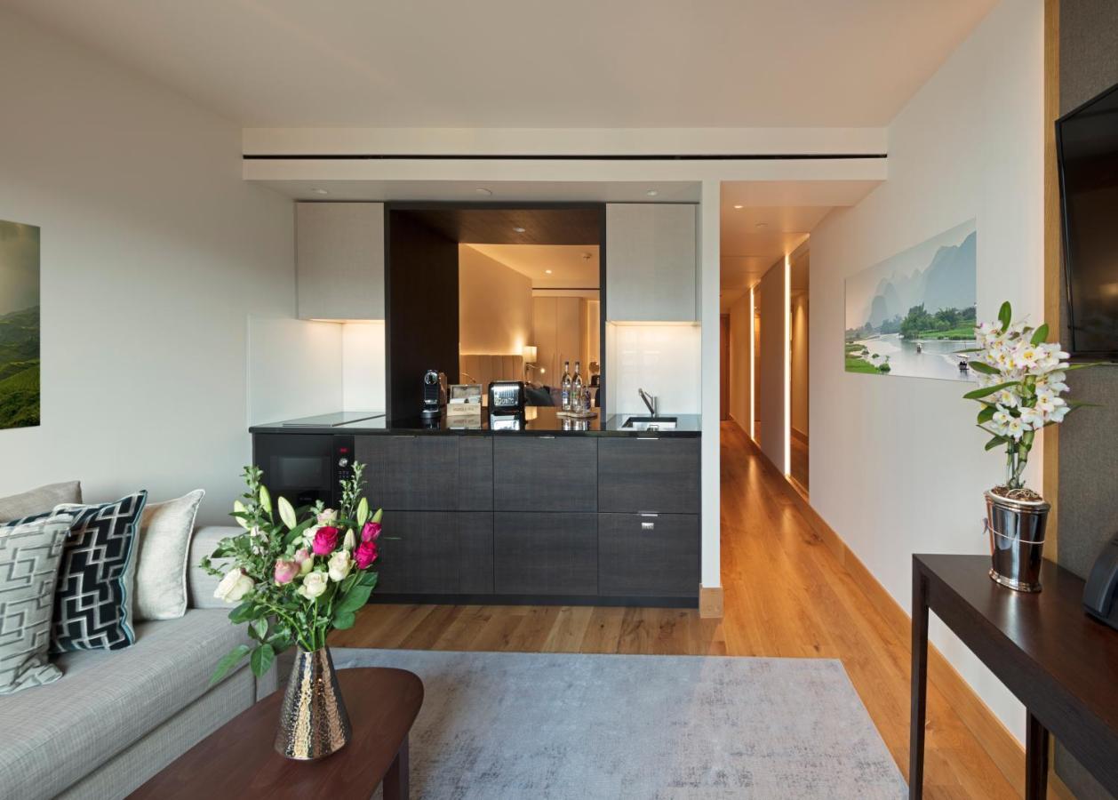 ทาวเวอร์ สวีท บาย บลู ออร์คิด Hotel ลอนดอน ภายนอก รูปภาพ The photo showcases a modern and stylish interior space, likely a living area of a luxurious apartment or hotel suite. 

- **Bar Area**: There is a sleek bar counter that features a variety of bottles and glassware, suggesting a well-equipped space f
