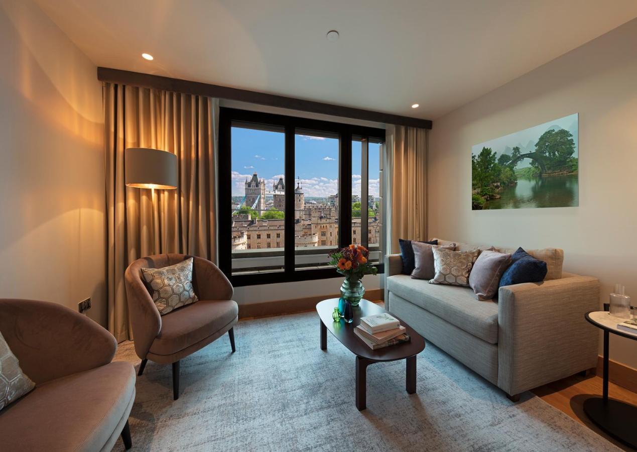 ทาวเวอร์ สวีท บาย บลู ออร์คิด Hotel ลอนดอน ภายนอก รูปภาพ The photo depicts a modern living room with a contemporary design. It features two stylish, circular chairs and a comfortable sofa adorned with various decorative pillows. A small coffee table is positioned in front of the sofa, topped with books and