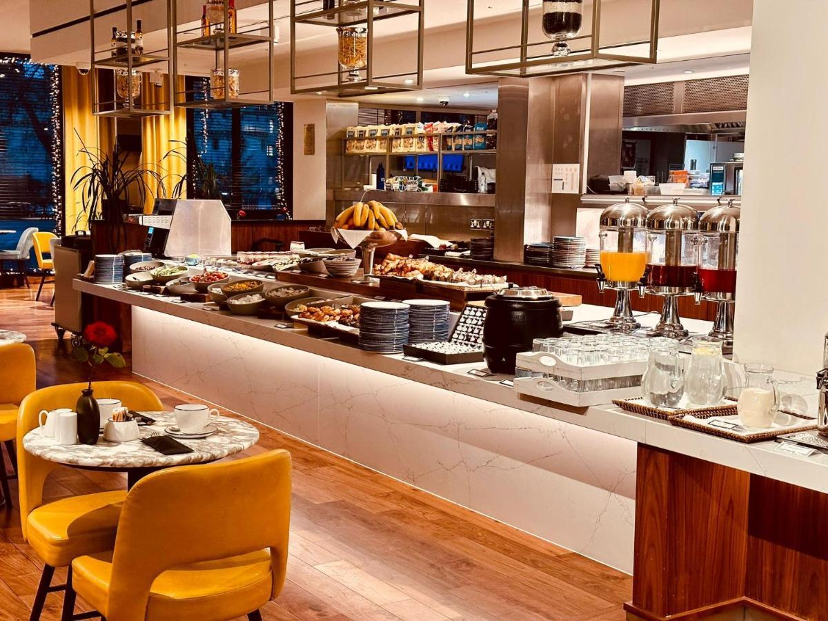 ทาวเวอร์ สวีท บาย บลู ออร์คิด Hotel ลอนดอน ภายนอก รูปภาพ The photo depicts a modern buffet setting, featuring an array of food items displayed elegantly on a long countertop. There are various dishes, likely including pastries, fruits, and other breakfast items, arranged neatly. In the background, there ar